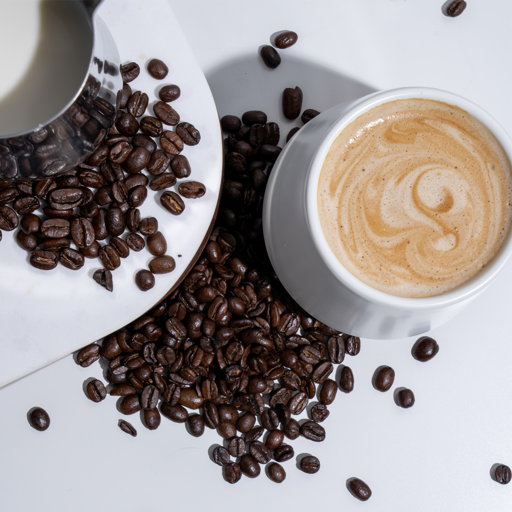 Flavored coffee beans with a coffee cup that includes coffee and cream.