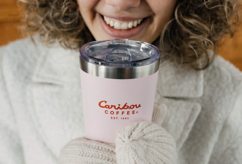 Woman smiling and holiday a Caribou Coffee pink tumbler