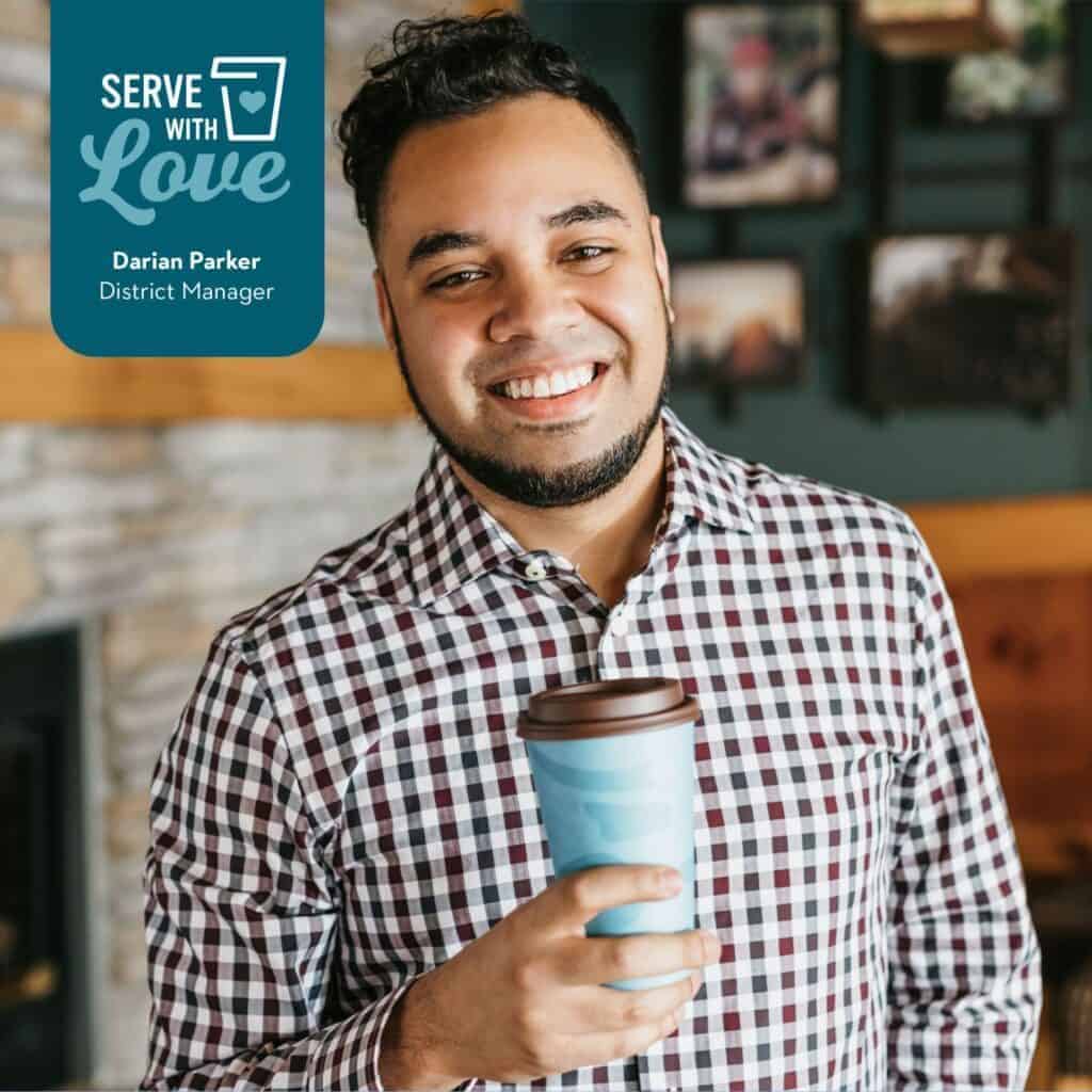 Headshot of District Manager Darian Parker smiling and holding a cup of Caribou Coffee