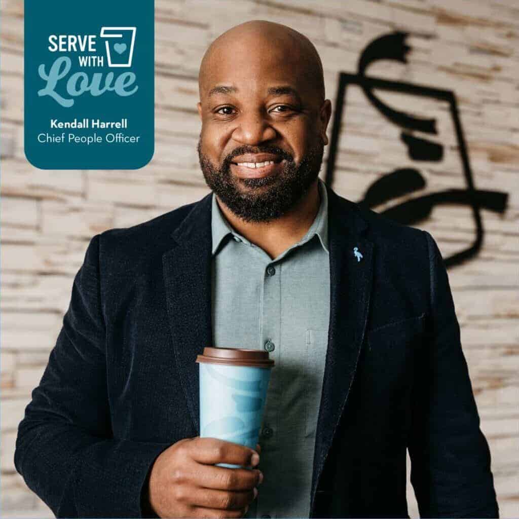 Headshot of Chief People Officer, Kendall Harrell smiling and holding a cup of Caribou Coffee