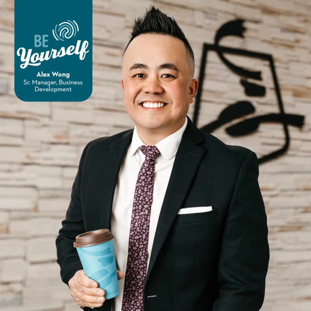 headshot of alex wong smiling while holding a cup of caribou coffee