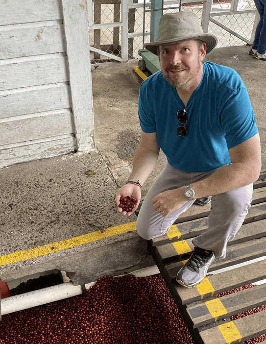 John butcher smiling while holding a handful of peaberries at La Minita farm in Costa Rica