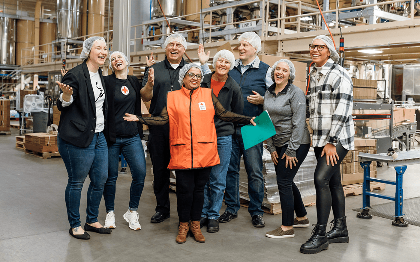 members of the red cross and caribou coffee smiling and laughing in the roastery at caribou coffee headquarters