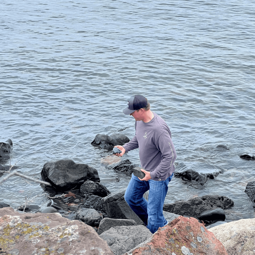 john butcher collecting rocks along the shoreline of lake superior