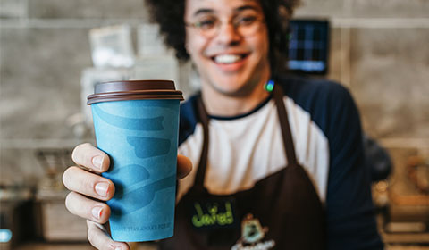 Caribou Coffee employee handing a coffee cup.