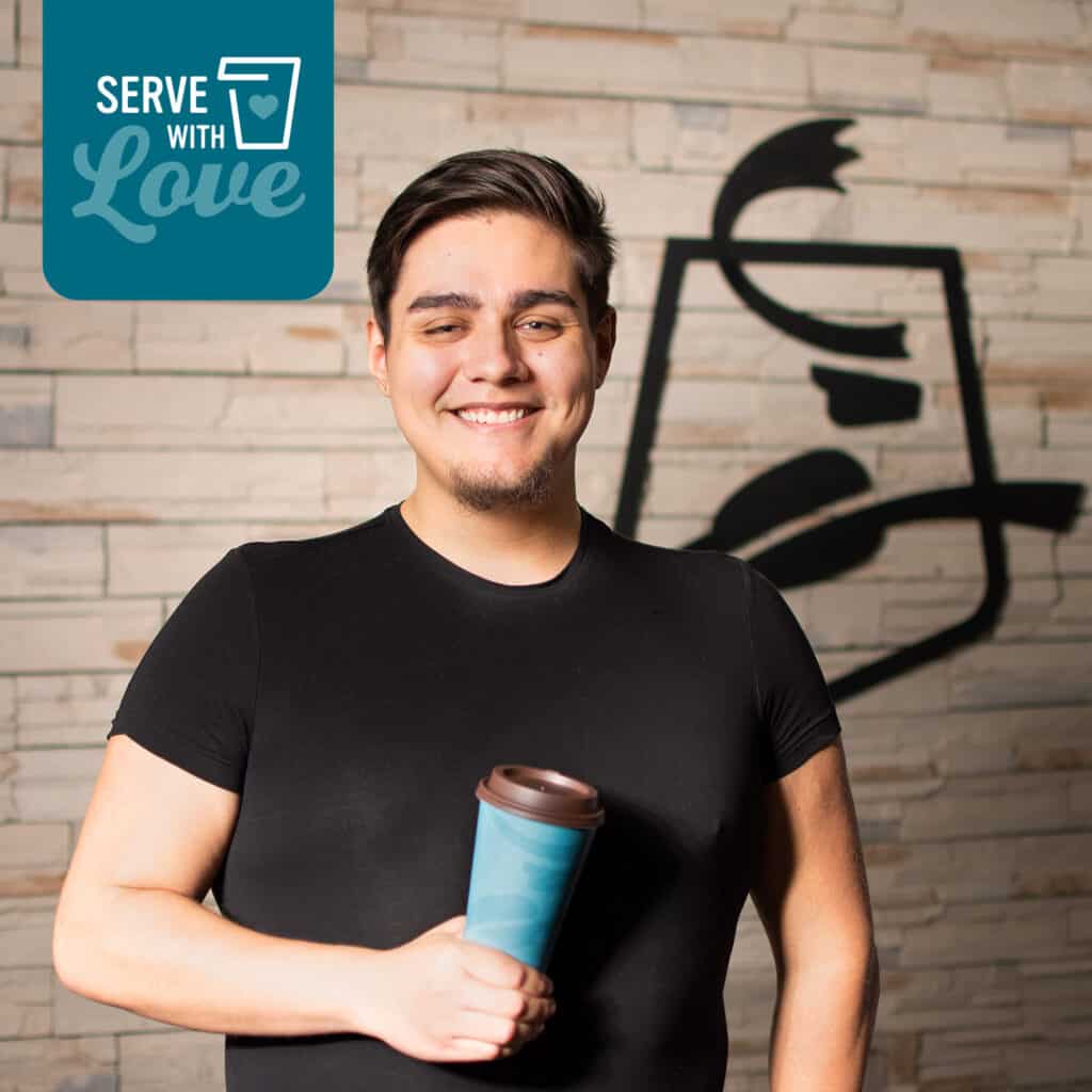 photo of Guest Relations Team Member Carlos Isais smiling while holding a caribou coffee cup