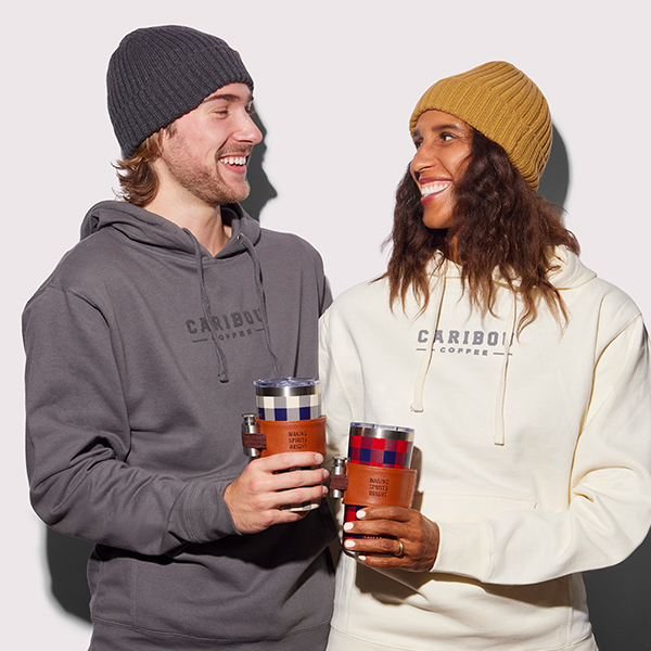 Two people smiling wearing Caribou Coffee apparel