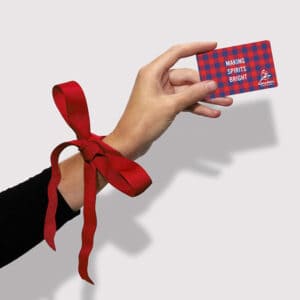 A hand with ribbon tied around the wrist holding a gift card