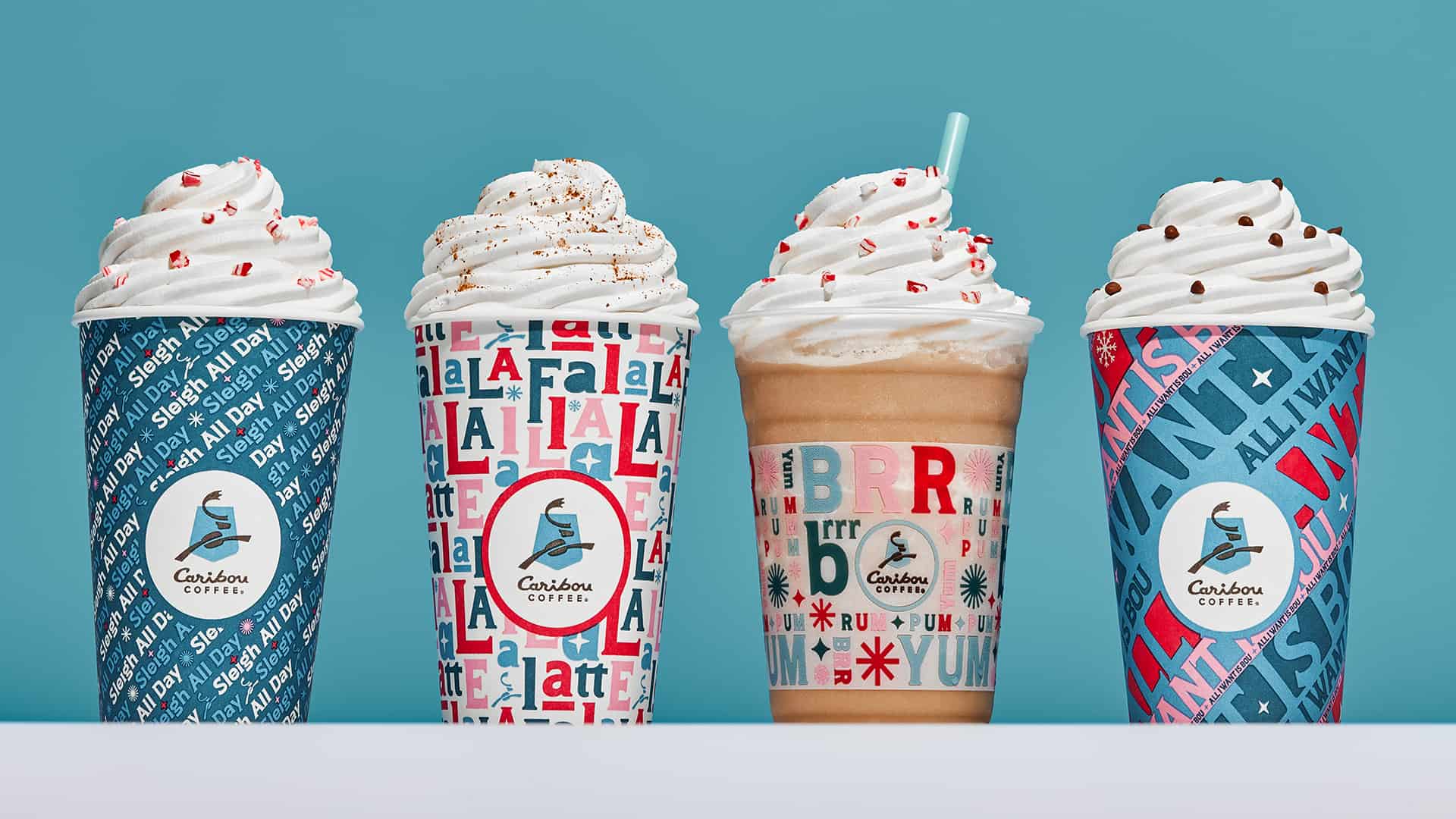 Four coffee drinks with whipped cream in festive cups on a blue background