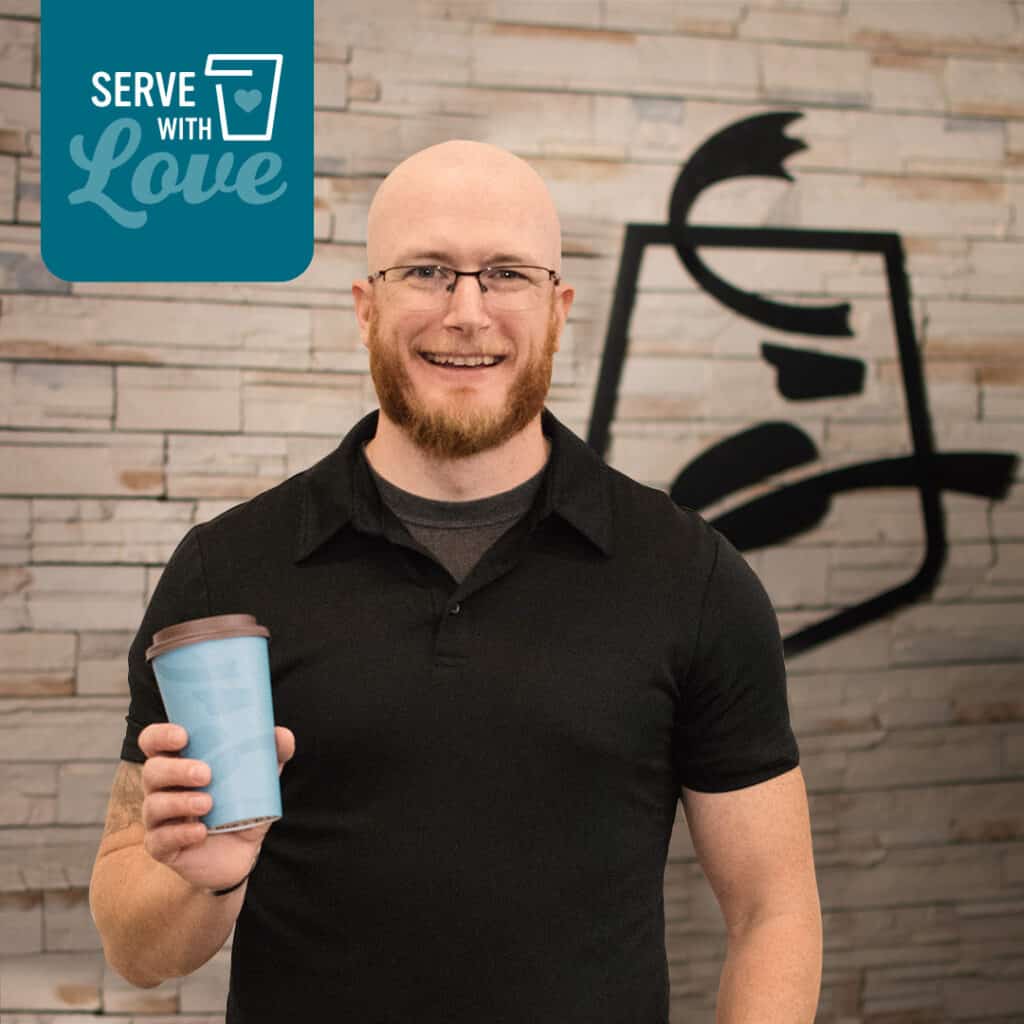 Caribou Coffee district manager Cory Fruit smiling while holding a cup of coffee
