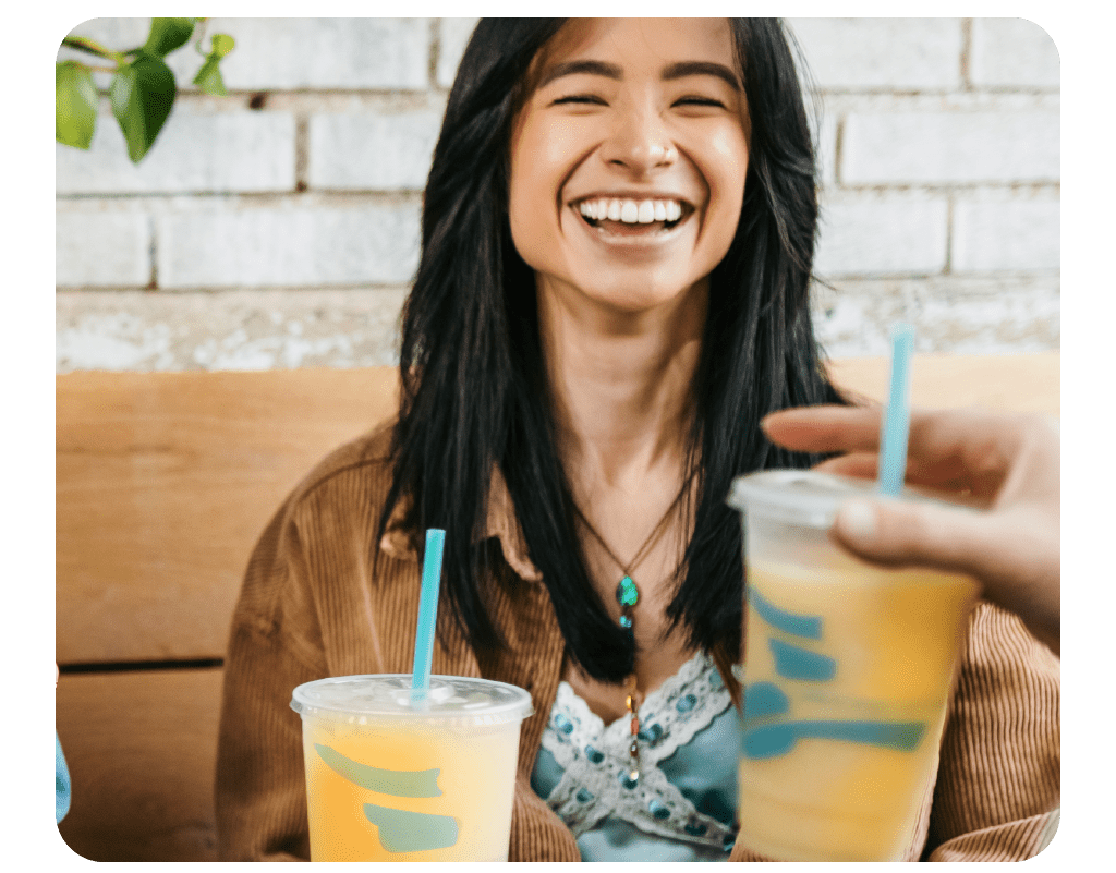 Woman smiling and drinking a Tangerine Pineapple Smoothie