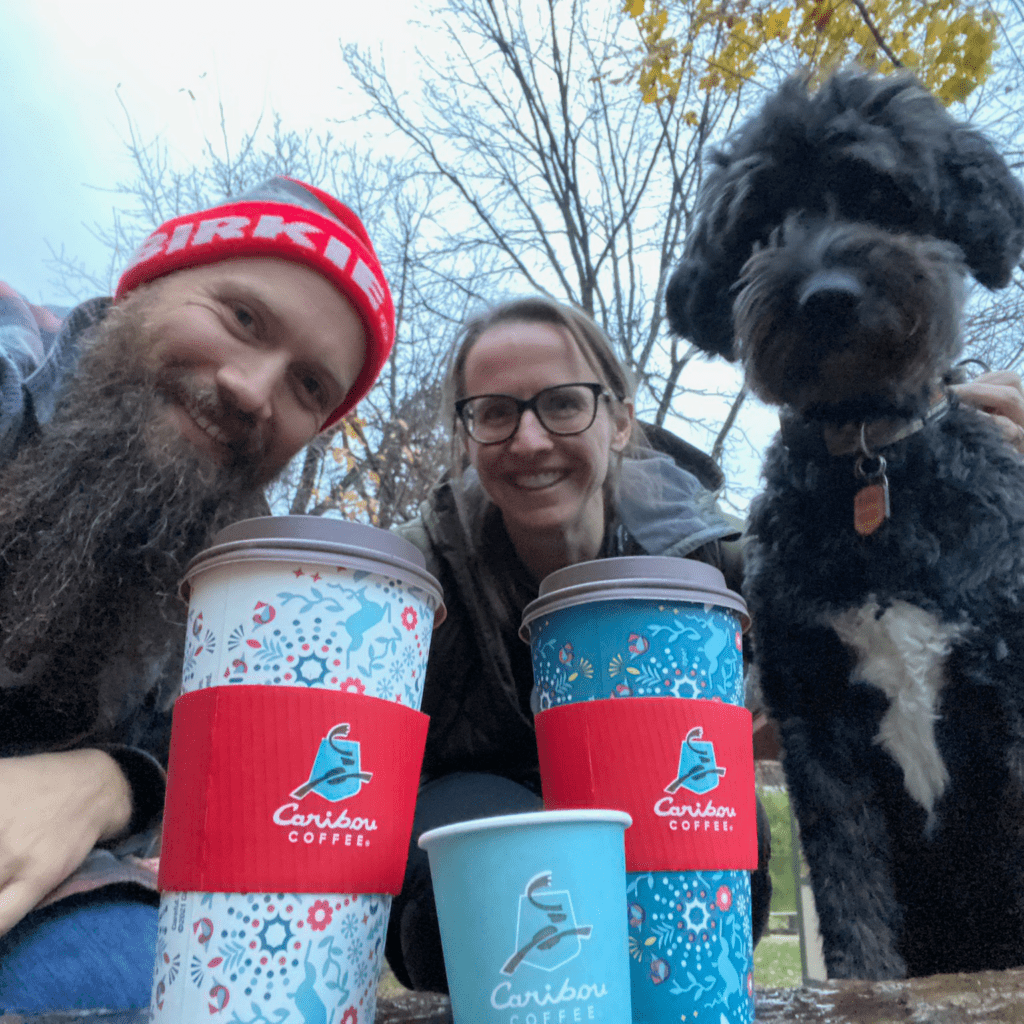 brian and kirstin tracy smiling with their dog with caribou cups in front of them