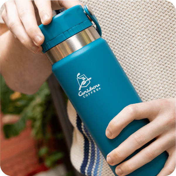 Person holding a blue Caribou Coffee water bottle