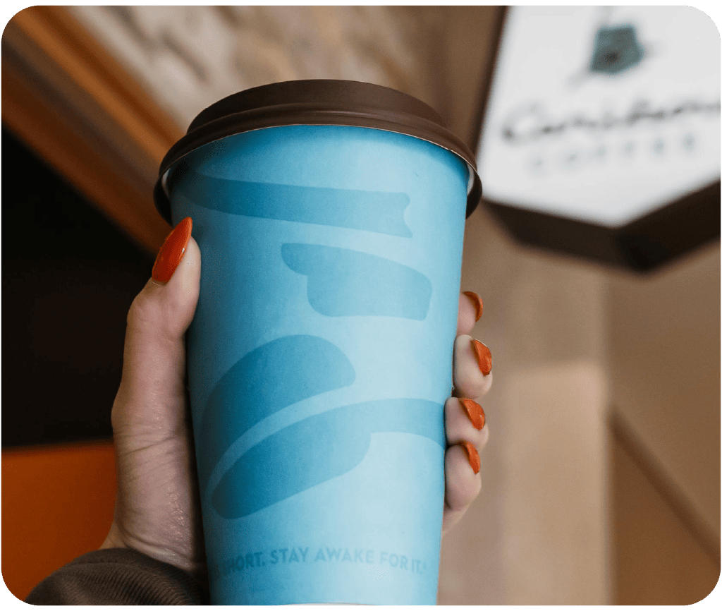 Hand holding a hot caribou coffee cup.