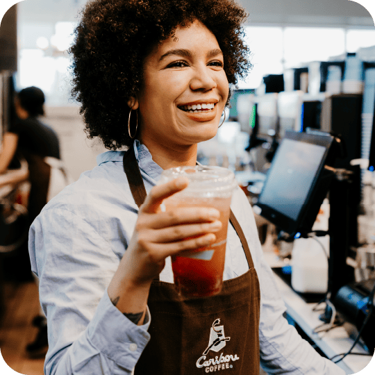 Barista smiling and handing off a drink.